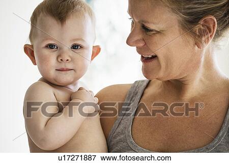 Stock Photo - Smiling mother holding baby girl. Fotosearch