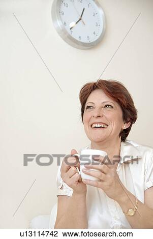 Stock Image - Smiling woman having cup of coffee. Fotosearch
