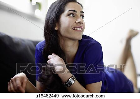 Stock Photo - Smiling woman laying on sofa. Fotosearch