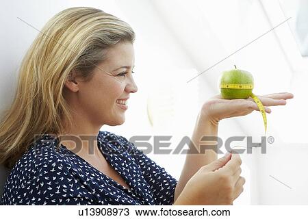 Smiling woman measuring apple View Large Photo Image Stock Image - Smiling woman measuring apple. Fotosearch