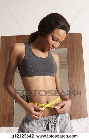 Smiling woman measuring her waistline View Large Photo Image Stock Image - Smiling woman measuring her waistline. Fotosearch