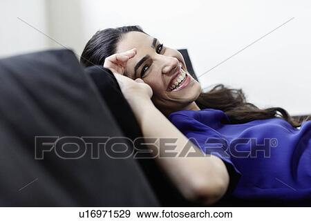 Stock Photo - Smiling woman relaxing on sofa. Fotosearch