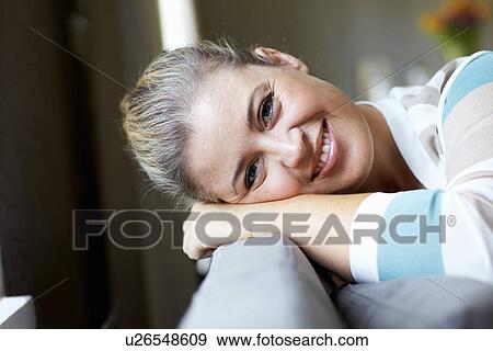 Smiling woman relaxing on sofa View Large Photo Image Stock Photo - Smiling woman relaxing on sofa. Fotosearch