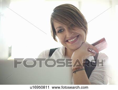 Stock Image - Smiling woman shopping online. Fotosearch