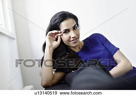 Smiling woman sitting on sofa View Large Photo Image Stock Photo - Smiling woman sitting on sofa. Fotosearch