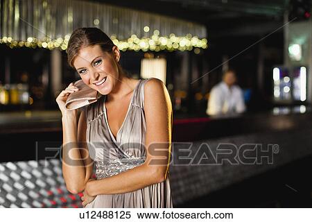 Stock Photography - Smiling woman standing in bar. Fotosearch