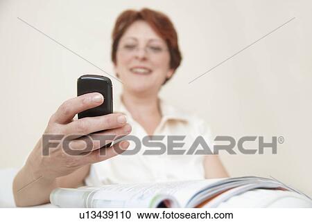 Stock Image - Smiling woman using cell phone. Fotosearch