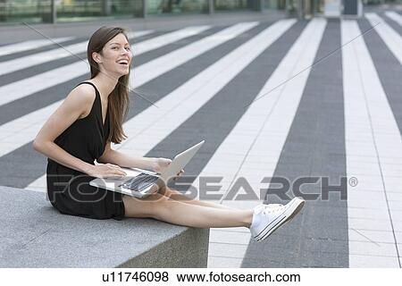 Smiling woman using laptop outdoors View Large Photo Image Stock Photo - Smiling woman using laptop outdoors. Fotosearch