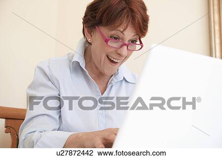 Stock Image - Smiling woman using laptop. Fotosearch