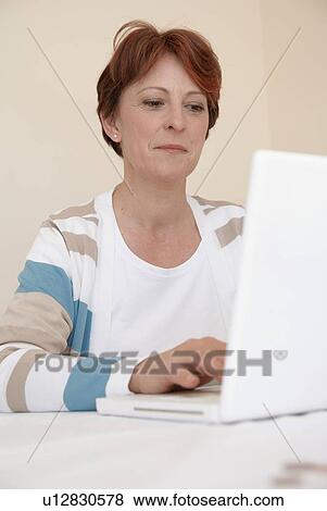Smiling woman using laptop View Large Photo Image Stock Photo - Smiling woman using laptop. Fotosearch