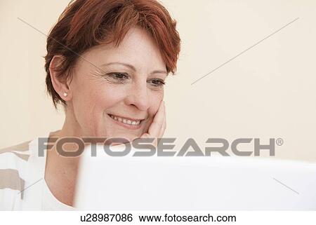 Stock Photograph - Smiling woman using laptop. Fotosearch