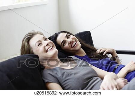 Smiling women relaxing on sofa View Large Photo Image Stock Image - Smiling women relaxing on sofa. Fotosearch