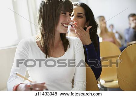Stock Photo - Students whispering in classroom. Fotosearch