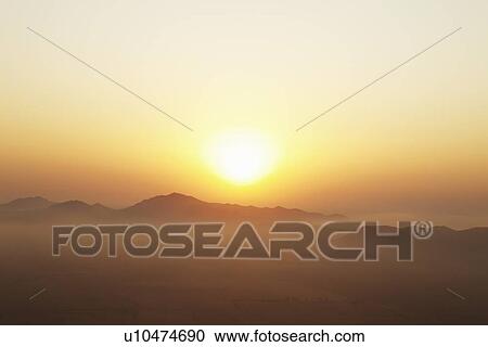 Sun setting over foggy landscape View Large Photo Image Stock Image - Sun setting over foggy landscape. Fotosearch