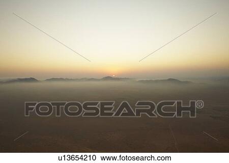 Stock Image - Sun setting over foggy landscape. Fotosearch