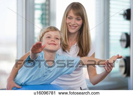 Stock Image - Trainer working with boy in gym. Fotosearch