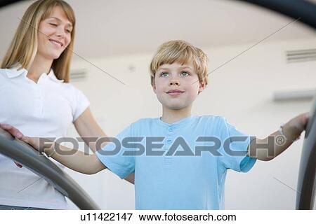 Stock Photo - Trainer working with boy in gym. Fotosearch