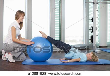 Trainer working with boy in gym View Large Photo Image Stock Photo - Trainer working with boy in gym. Fotosearch