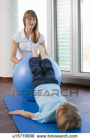 Stock Photo - Trainer working with boy in gym. Fotosearch