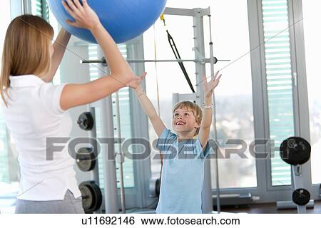 Stock Photograph - Trainer working with boy in gym. Fotosearch