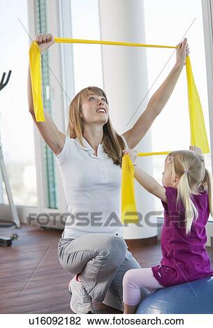 Stock Image - Trainer working with girl in gym. Fotosearch