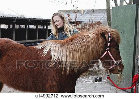 Stock Image - Woman brushing horse outdoors. Fotosearch