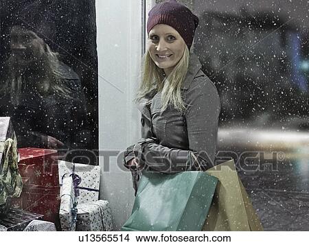 Picture - Woman carrying shopping bags in snow. Fotosearch