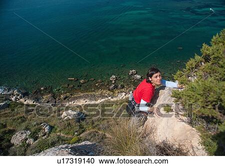 Woman climbing rocky coastal cliff View Large Photo Image Stock Image - Woman climbing rocky coastal cliff. Fotosearch