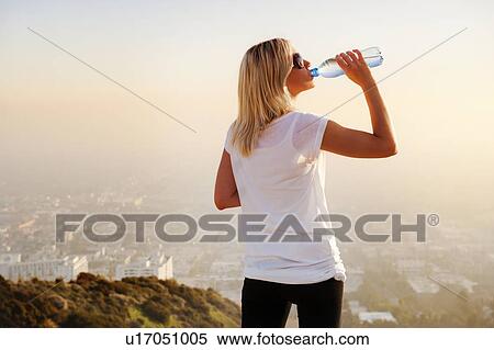 Woman drinking water on hilltop View Large Photo Image Stock Photography - Woman drinking water on hilltop. Fotosearch