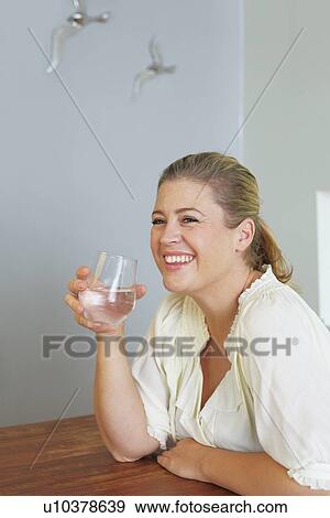 Stock Photo - Woman having glass of water at table. Fotosearch