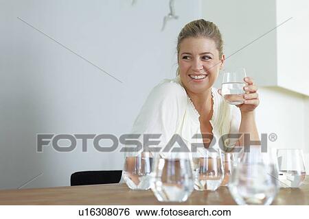 Stock Photograph - Woman having glass of water at table. Fotosearch