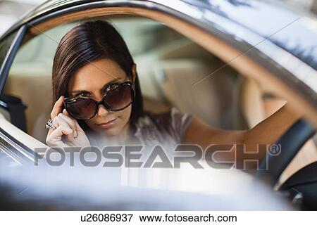 Woman peering over sunglasses in car View Large Photo Image Stock Photo - Woman peering over sunglasses in car. Fotosearch