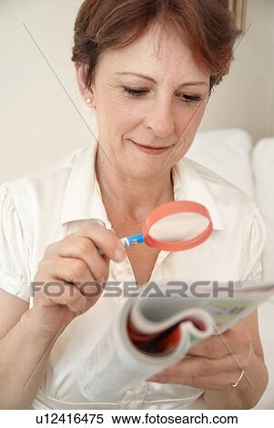 Stock Photography - Woman reading with magnifying glass. Fotosearch