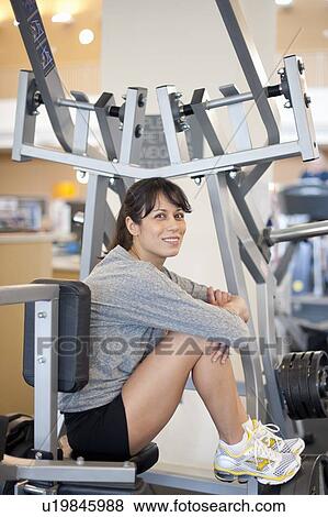 Woman sitting on exercise machine in gym View Large Photo Image Stock Photo - Woman sitting on exercise machine in gym. Fotosearch