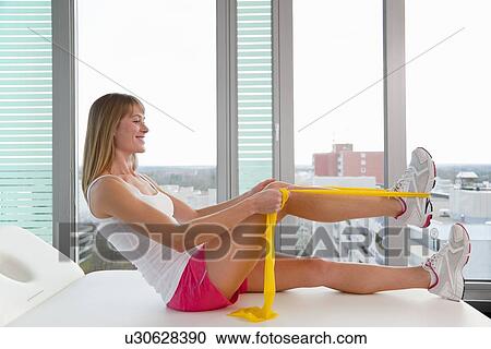 Stock Image - Woman stretching in doctors office. Fotosearch