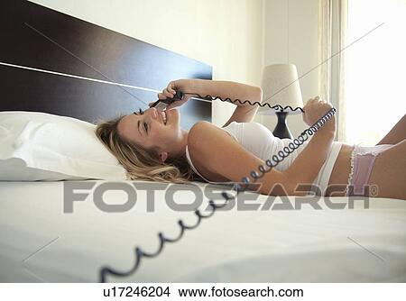 Picture - Woman talking on phone in bed. Fotosearch