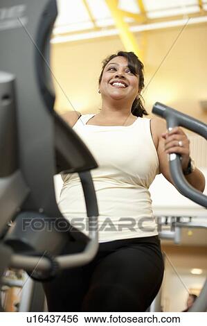 Woman using elliptical machine in gym View Large Photo Image Stock Photograph - Woman using elliptical machine in gym. Fotosearch