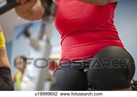 Stock Image - Woman using spin machine in gym. Fotosearch
