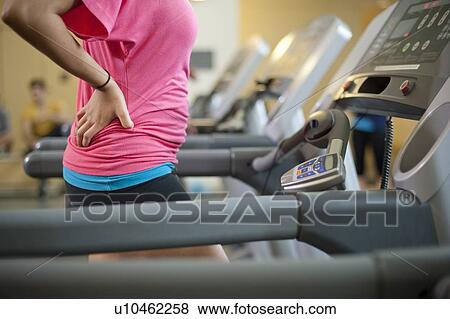 Stock Photo - Woman using treadmill in gym. Fotosearch