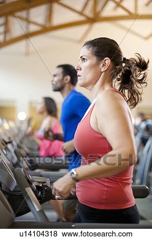Stock Photo - Woman using treadmill in gym. Fotosearch