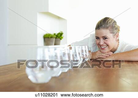 Stock Image - Woman with glasses of water on table. Fotosearch