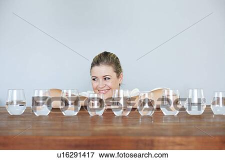 Woman with glasses of water on table View Large Photo Image Stock Photo - Woman with glasses of water on table. Fotosearch