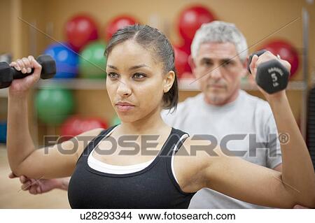 Picture - Woman working with trainer in gym. Fotosearch