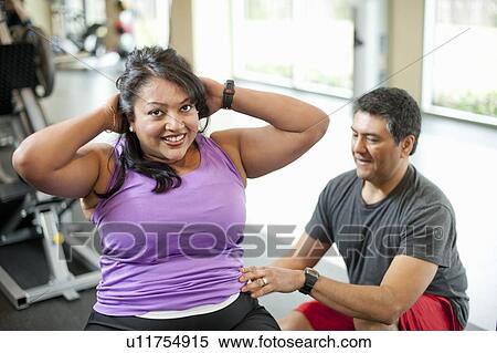 Stock Photography - Woman working with trainer in gym. Fotosearch