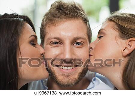 Women kissing smiling mans cheeks View Large Photo Image Stock Photo - Women kissing smiling mans cheeks. Fotosearch