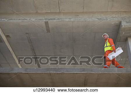 Worker carrying blueprints on site View Large Photo Image Stock Image - Worker carrying blueprints on site. Fotosearch