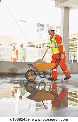 Worker carting concrete on site View Large Photo Image Stock Photo - Worker carting concrete on site. Fotosearch