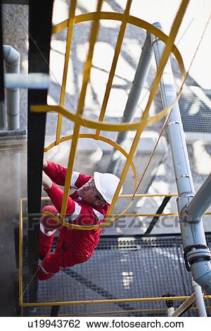 Worker climbing ladder at oil refinery View Large Photo Image Stock Image - Worker climbing ladder at oil refinery. Fotosearch