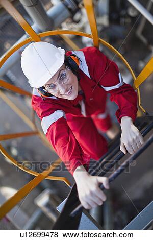 Worker climbing ladder at oil refinery View Large Photo Image Stock Photo - Worker climbing ladder at oil refinery. Fotosearch