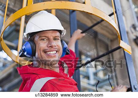 Worker climbing ladder at oil refinery View Large Photo Image Stock Photo - Worker climbing ladder at oil refinery. Fotosearch